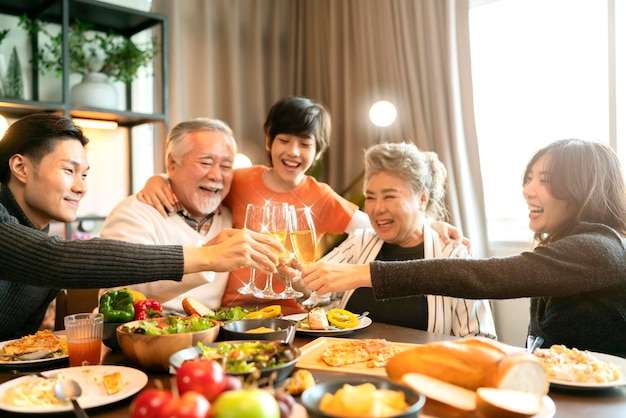 Free photo asian multi generation grandparent grandchild happiness joyful dinner together at homeholidays celebration and people concept happy friends with sparklers having christmas thanksgiving dinner