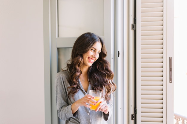Free photo cheerful woman with juice near window