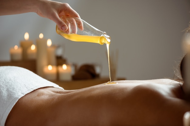 Free photo honey pouring on woman's naked back in spa salon.
