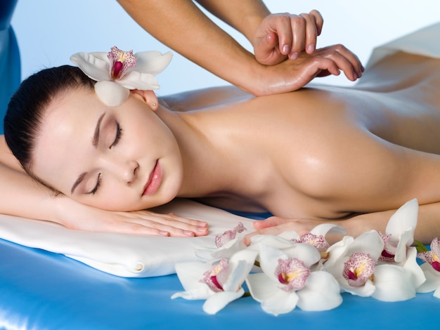 Relaxing massage of back for young beautiful woman in spa salon - horizontal