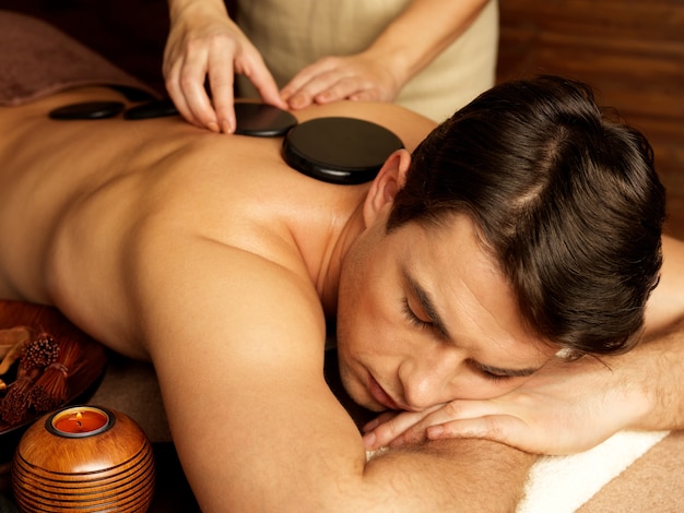 Free photo handsome man having stone massage in spa salon. healthy lifestyle.
