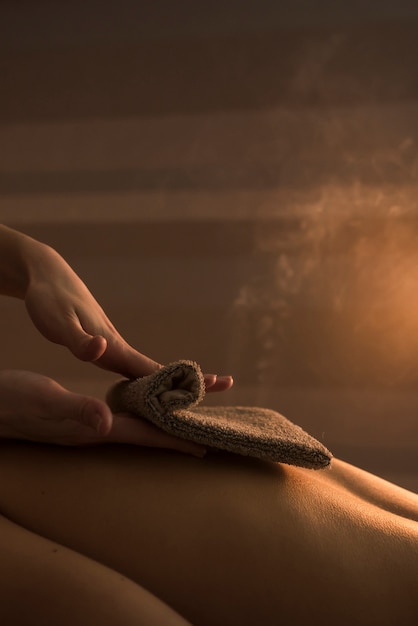 Free photo beautician hand massaging woman's back with hot towel in spa